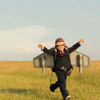 small boy running wearing an airplane costume